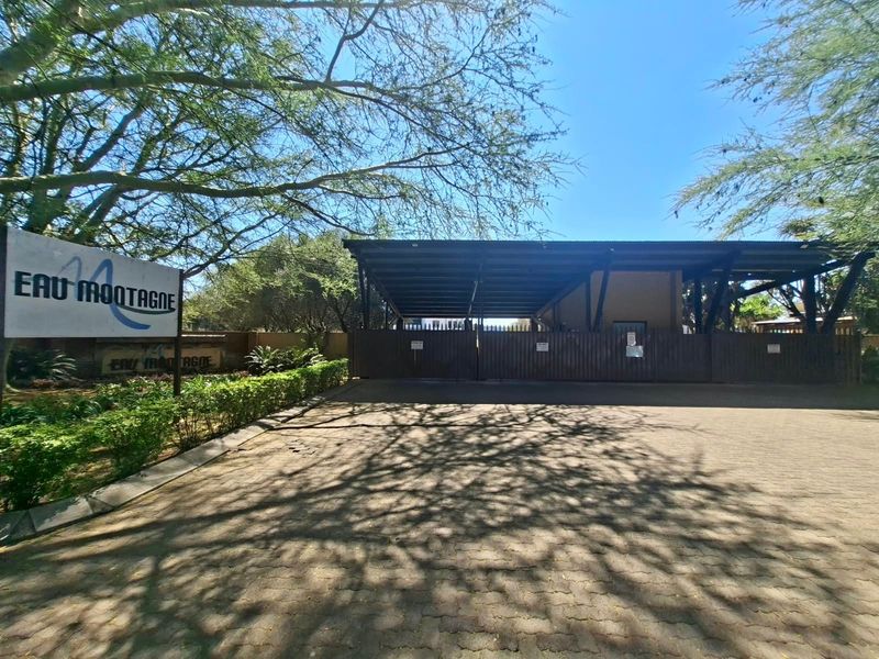 The entrance to the Eau Montagne property features a paved driveway, secure gated access, and a covered structure.