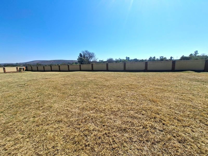 A spacious, level vacant residential plot enclosed by a solid perimeter boundary wall, offering a clear canvas for future development.