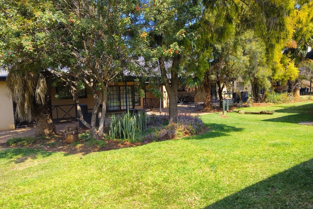 A well-maintained rear garden featuring a paved patio area, mature trees, and established landscaping, providing a private outdoor space.