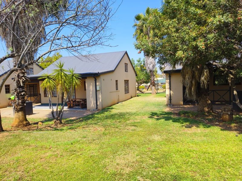 Rear view of the townhouse featuring a paved patio area, established garden, and metal roofing.