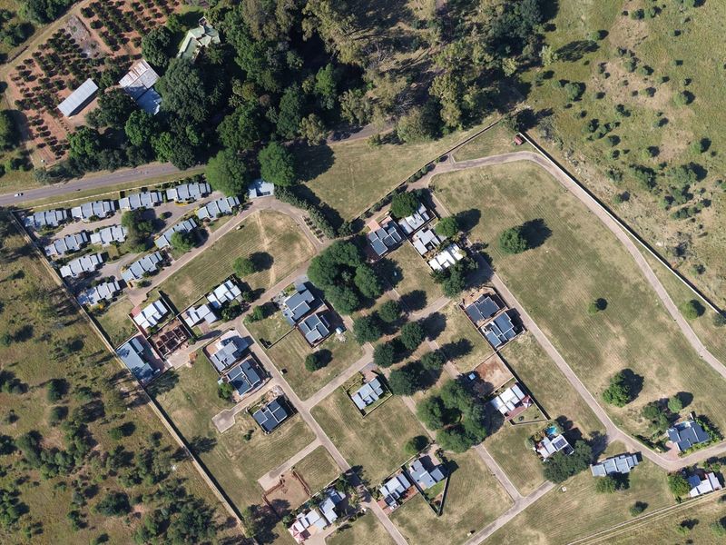 An aerial view of a residential estate development featuring multiple plots, paved internal roads, and established perimeter fencing within a rural landscape.