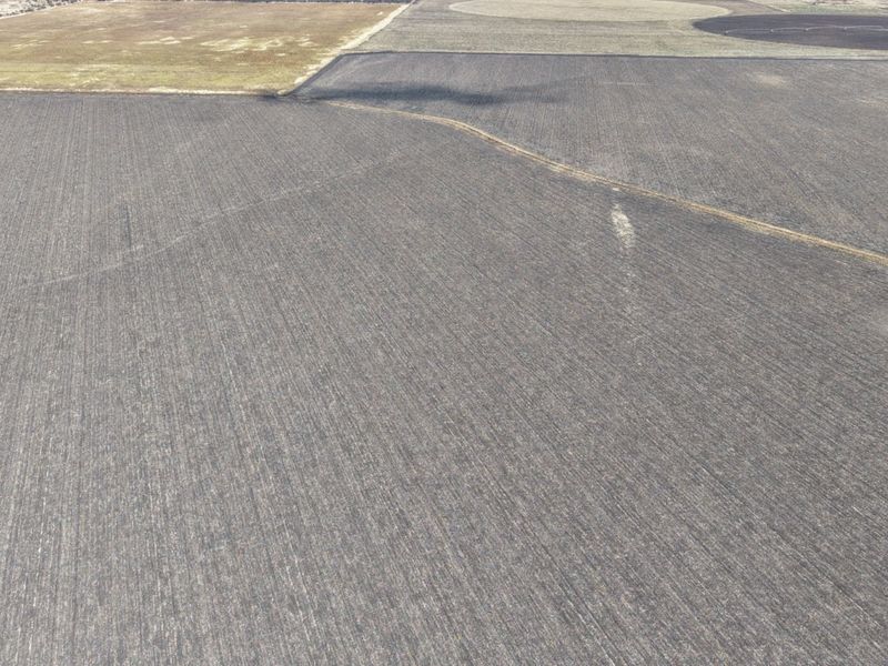 An aerial view of expansive, tilled agricultural farmland, showcasing the vast open landscape and soil preparation for farming.