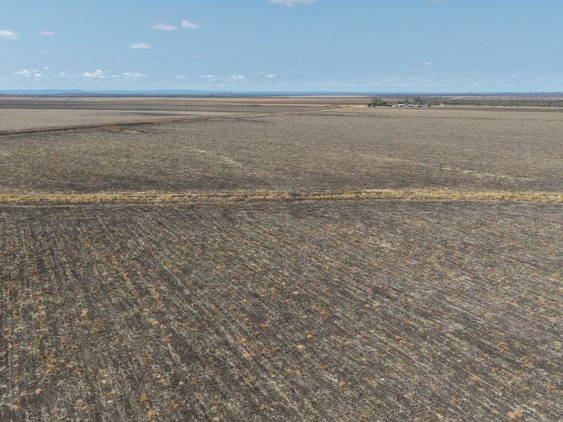An expansive aerial view of a large, flat agricultural farm property with vast open fields and distant farm infrastructure.