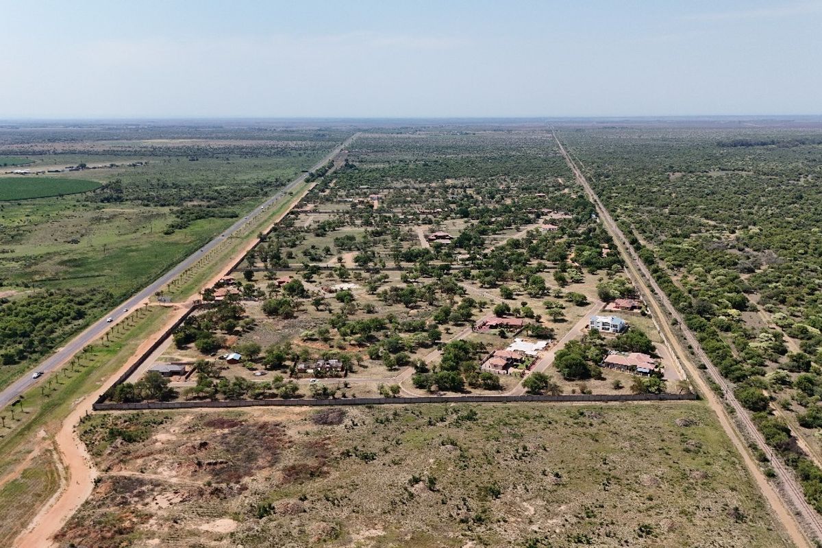 An aerial view of a residential estate development featuring multiple plots, perimeter fencing, and surrounding natural landscape.