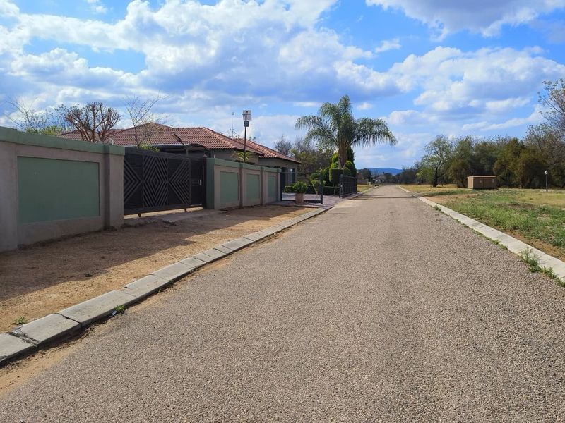 A view of the paved street approach featuring a perimeter wall and gated entrance to the residential property.