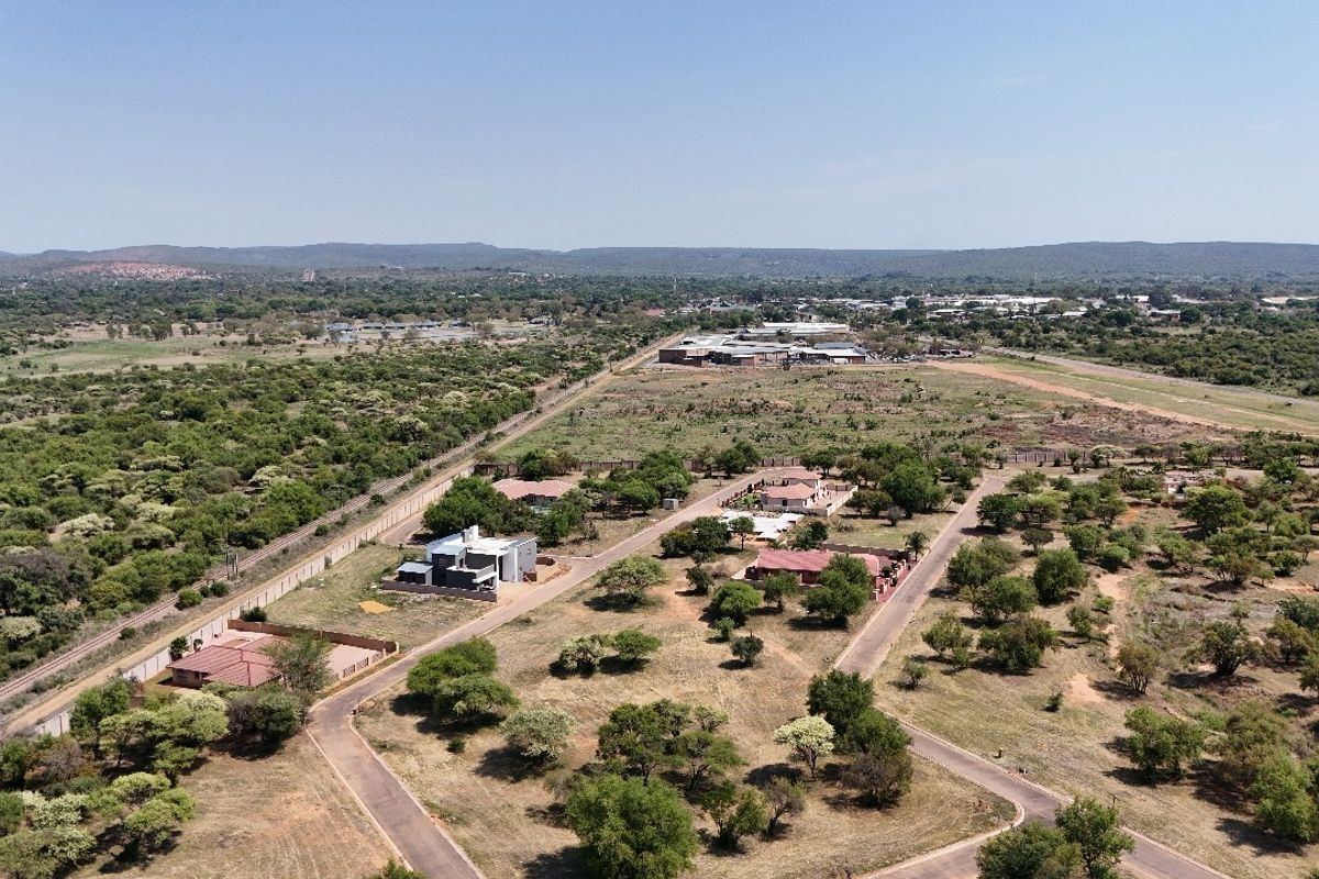 An aerial view of a residential development area featuring established roads, perimeter fencing, and surrounding natural landscape.