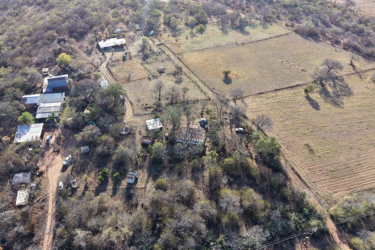 Aerial view of a small holding property featuring multiple outbuildings, fenced paddocks, and extensive natural vegetation across the rural landscape.