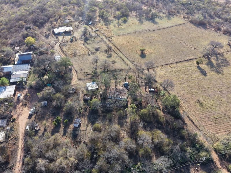 Aerial view of a small holding property featuring multiple outbuildings, fenced paddocks, and extensive natural vegetation across the rural landscape.