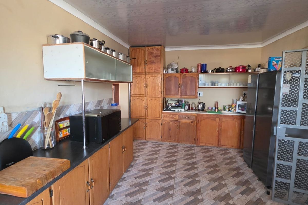 A functional kitchen featuring traditional wooden cabinetry, patterned floor tiles, and a tiled backsplash, offering ample storage and workspace for daily meal preparation.