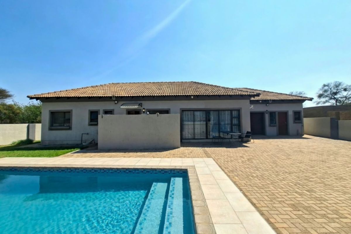 Rear view of the house featuring a paved patio area, swimming pool, and well-maintained exterior finishes.
