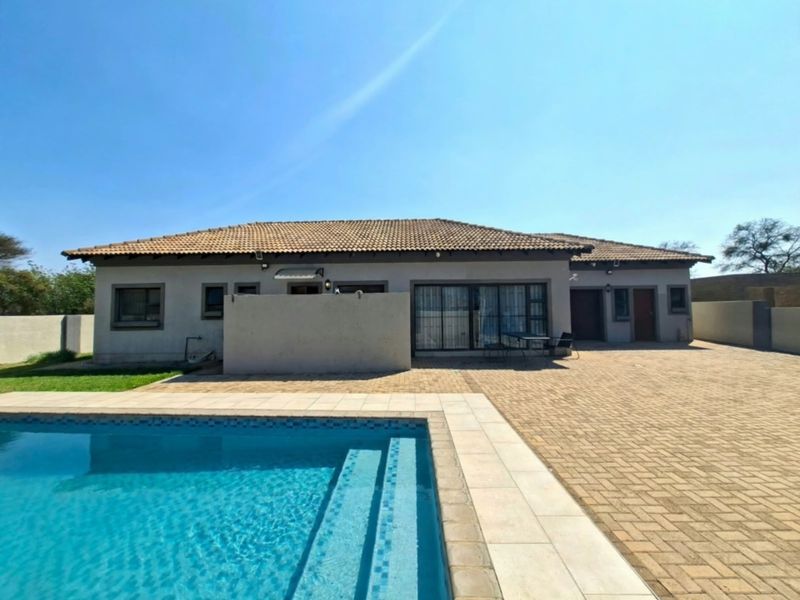 Rear view of the house featuring a paved patio area, swimming pool, and well-maintained exterior finishes.