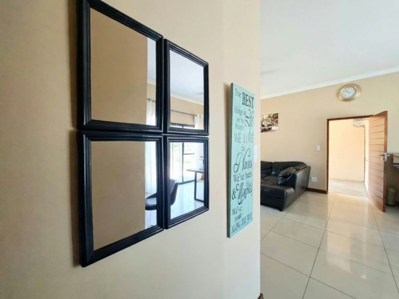 A view through a tiled hallway leading into an adjacent living area with neutral wall tones.