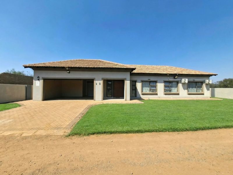 Front elevation of a well-maintained single-story house featuring a paved driveway, double garage, and a neat front lawn.