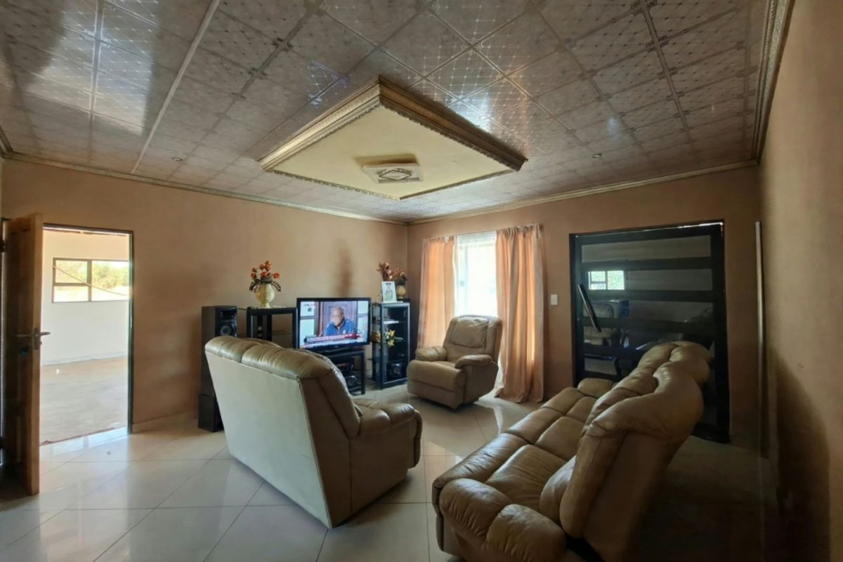 A living room featuring tiled flooring and a decorative drop ceiling with recessed lighting, providing a functional and lived-in space.