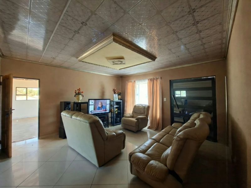 A living room featuring tiled flooring and a decorative drop ceiling with recessed lighting, providing a functional and lived-in space.