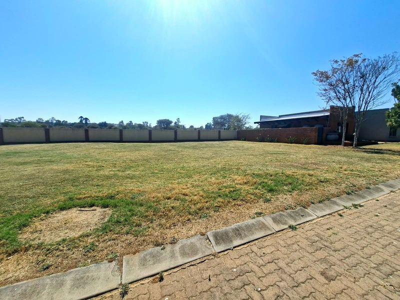 A spacious, level residential plot featuring a well-defined perimeter wall and established lawn, offering a clear canvas for future development.