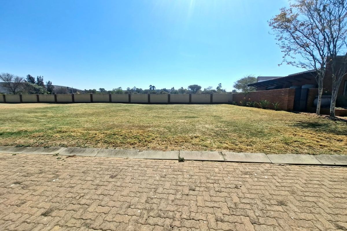 A spacious, level residential plot featuring a well-maintained lawn, paved driveway access, and secure perimeter walling.