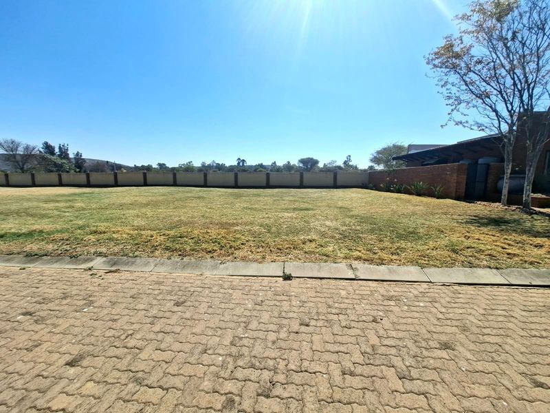 A spacious, level residential plot featuring a well-maintained lawn, paved driveway access, and secure perimeter walling.