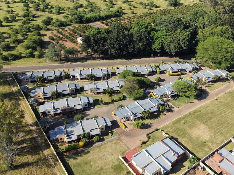 Aerial view of a residential complex featuring multiple housing units, paved internal roads, and surrounding landscaped grounds.