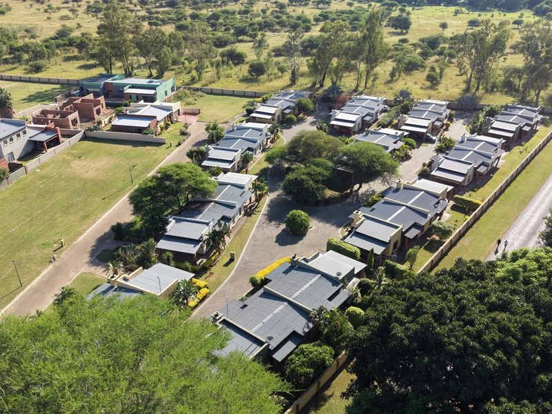 An aerial view of a residential estate featuring multiple housing units, paved internal roads, and established landscaping within a secure perimeter.