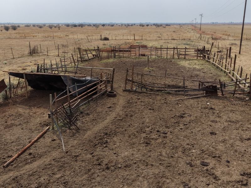 An outdoor livestock enclosure or corral area featuring weathered wooden fencing and basic animal containment infrastructure on a rural farm property.