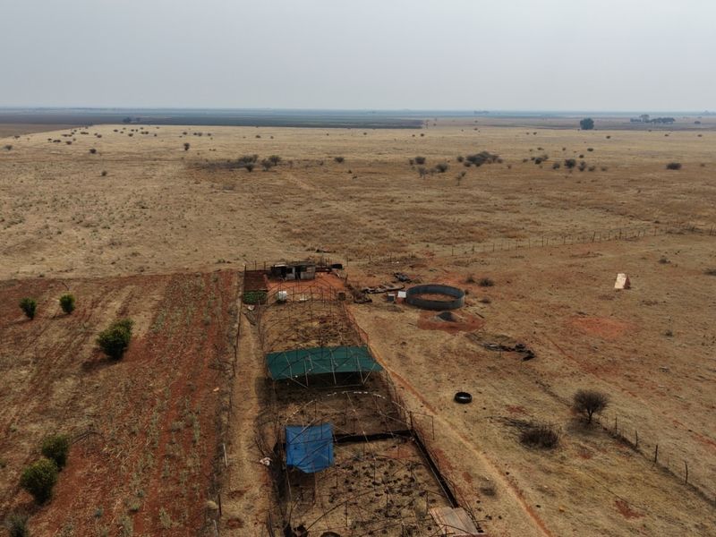 Aerial view of a large farm property featuring expansive open grazing land, agricultural enclosures, and a circular water reservoir.