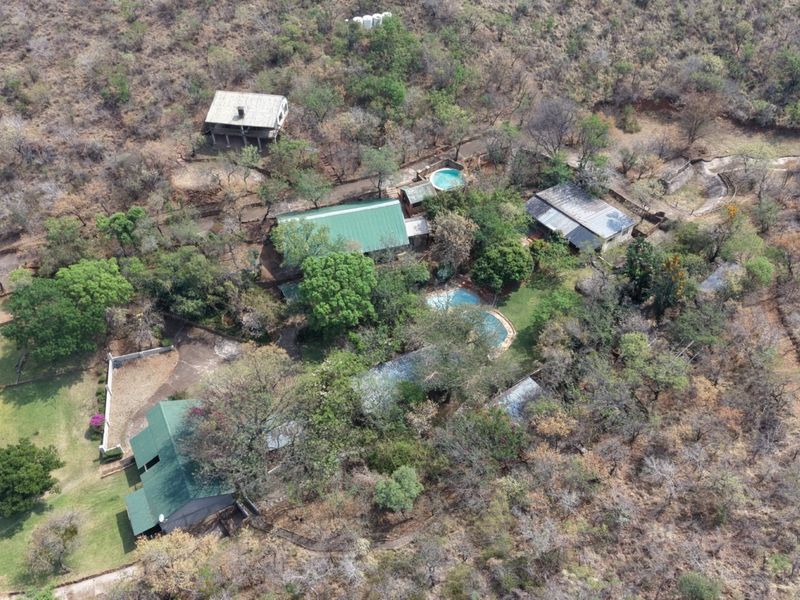 Aerial view of a rural farm property featuring multiple structures, a swimming pool, and extensive natural vegetation.