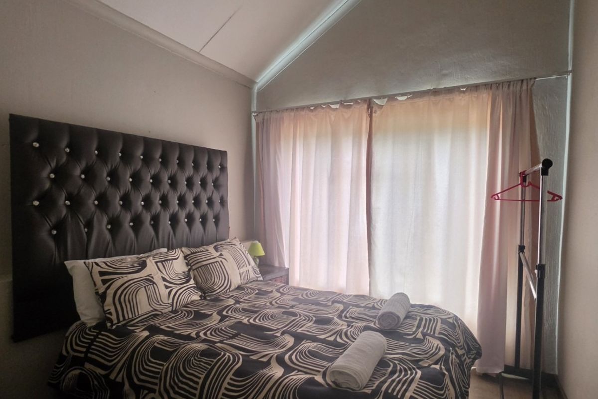 A bedroom featuring a vaulted ceiling and a large sliding glass door that provides natural light.