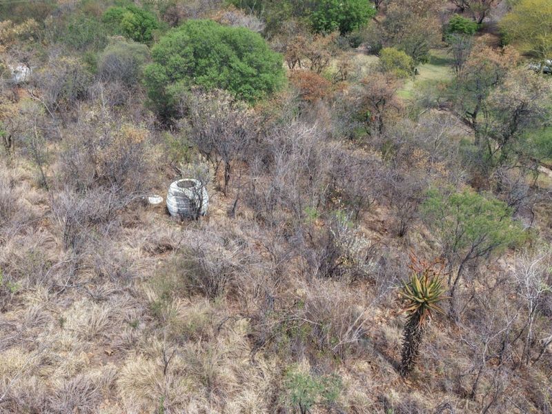 An aerial view of the farm landscape featuring natural vegetation and a visible water storage tank on the property.