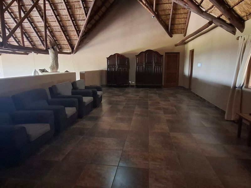 Spacious living area featuring a high vaulted thatched ceiling with exposed timber trusses and durable tiled flooring.
