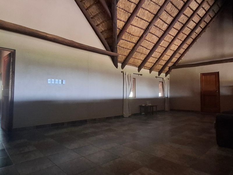 Spacious living area featuring a high vaulted thatched ceiling with exposed timber beams and durable tiled flooring.
