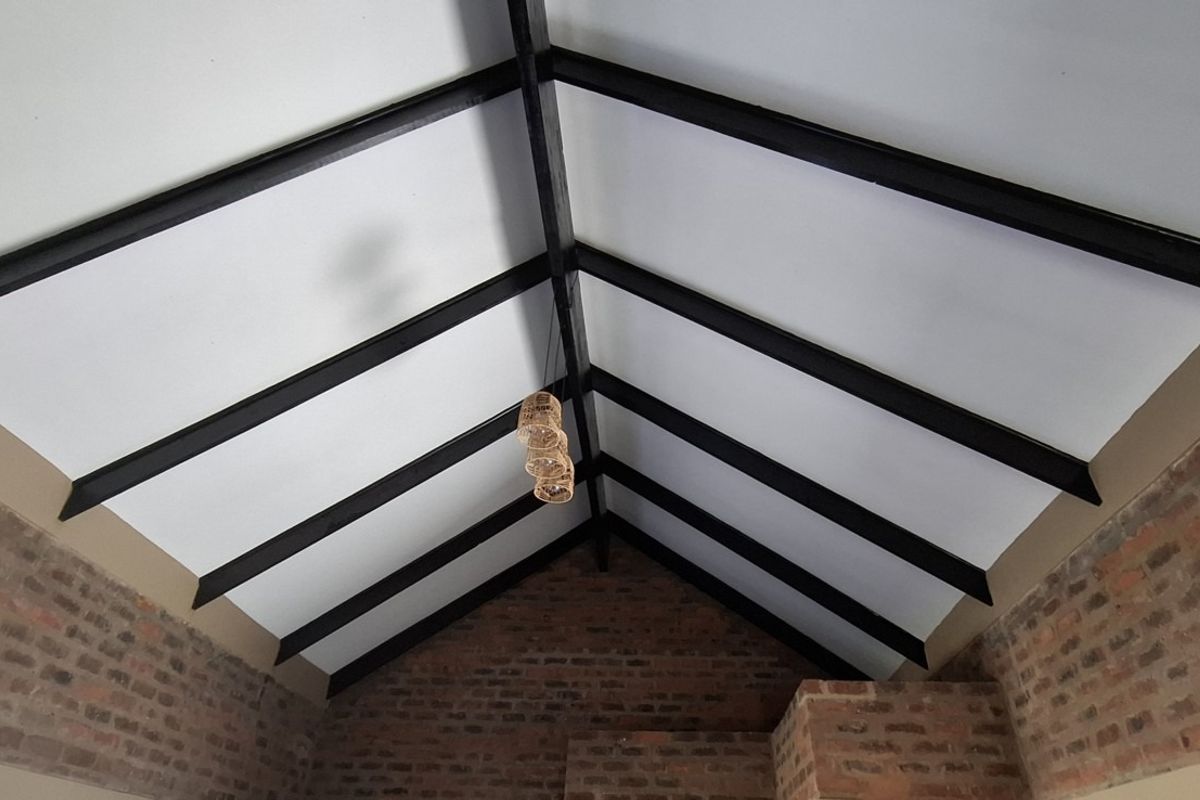 Spacious living area featuring a high vaulted ceiling with exposed timber beams and rustic exposed brick walls.