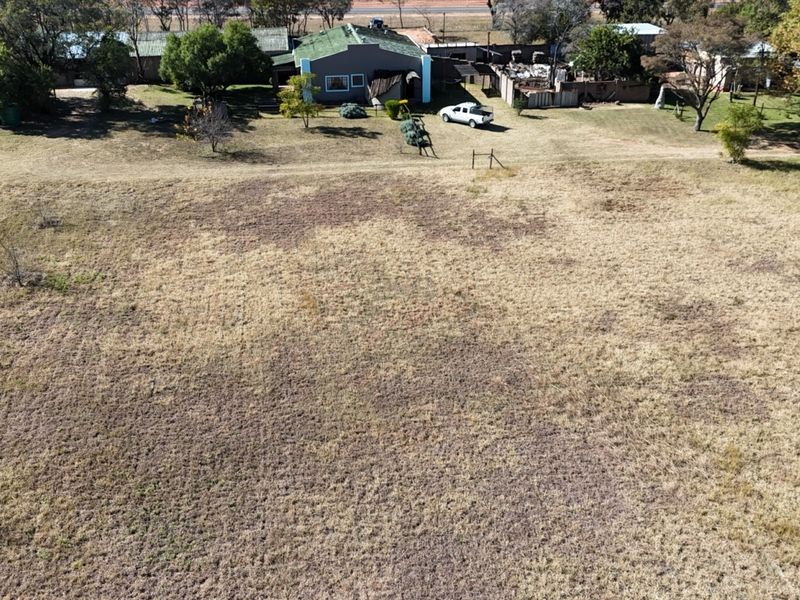 Aerial view of a farm property featuring a main dwelling, surrounding grounds, and perimeter fencing in a rural setting.
