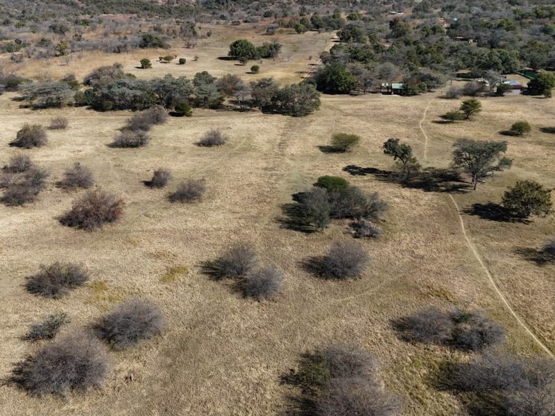 An aerial view of the expansive farm property featuring open grazing land, scattered indigenous trees, and established dirt tracks across the landscape.