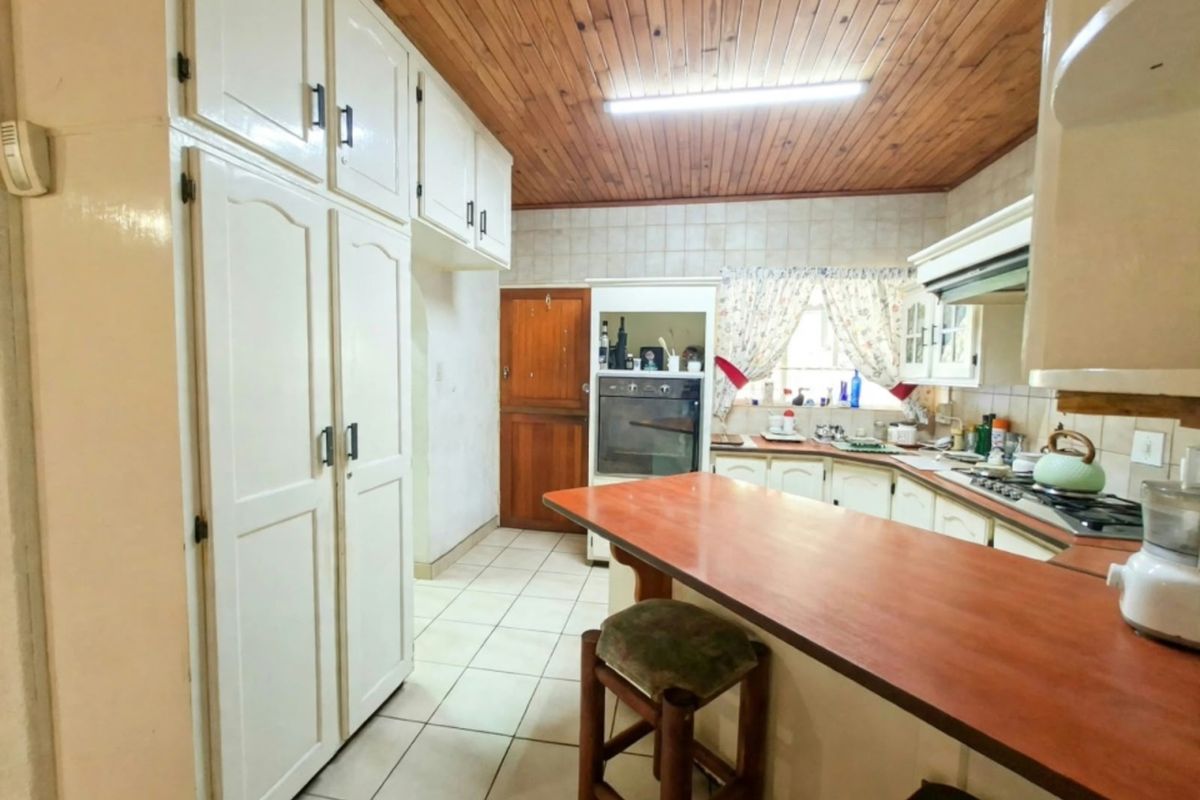 A functional kitchen featuring timber ceilings, built-in cabinetry, a breakfast counter, and integrated cooking appliances, offering potential for a modern renovation.