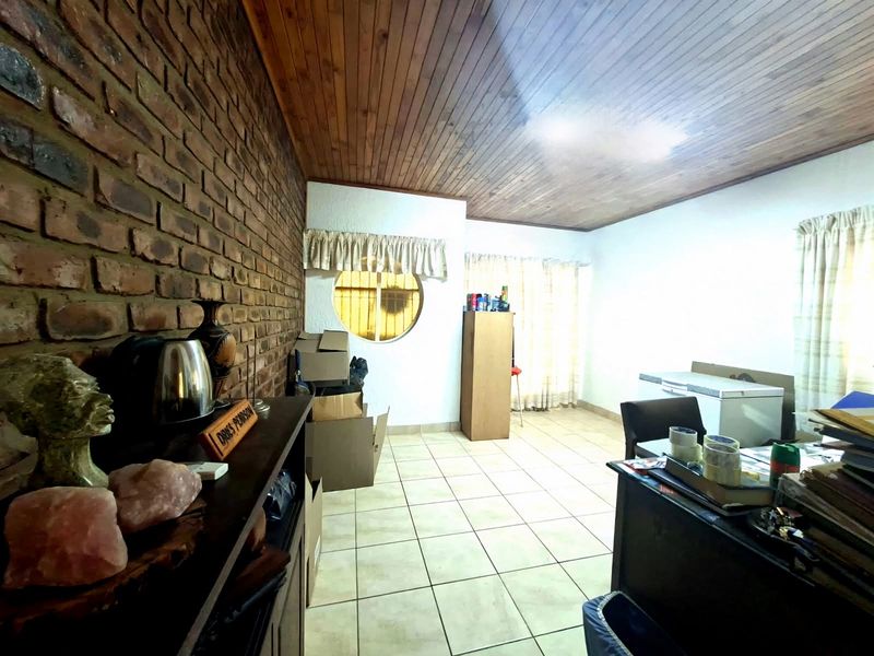 Living area featuring an exposed brick feature wall, timber ceiling, and ceramic floor tiles with a unique circular window.