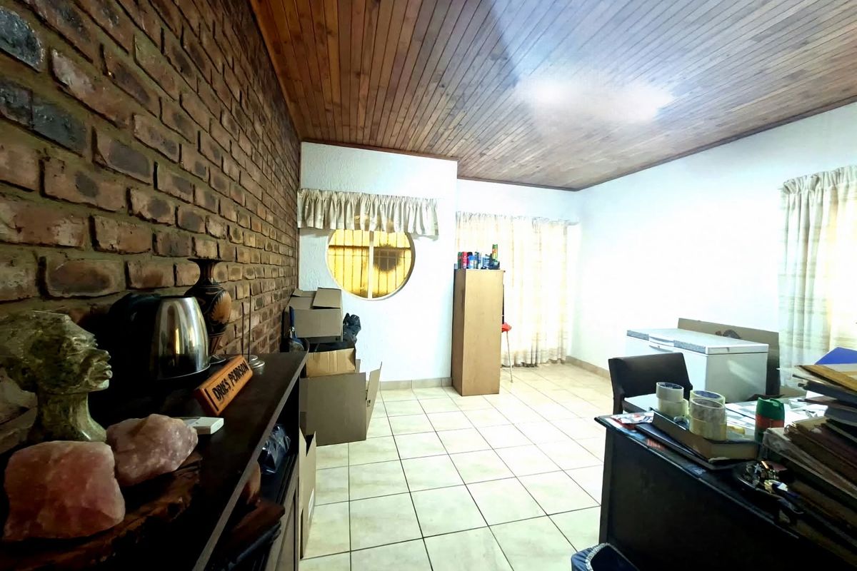 Living area featuring an exposed brick feature wall, timber ceiling, and ceramic floor tiles with a unique circular window.