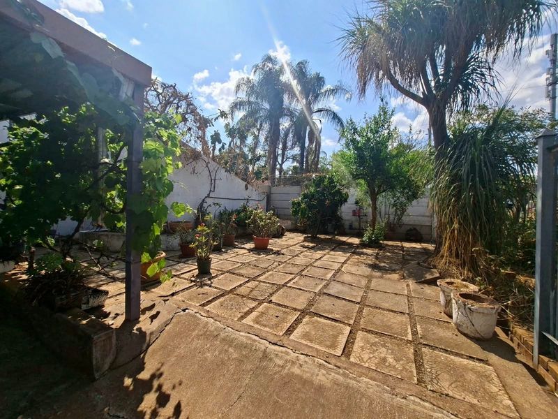 A paved outdoor garden area featuring a pergola structure and retaining walls, offering potential for landscaping and outdoor living improvements.