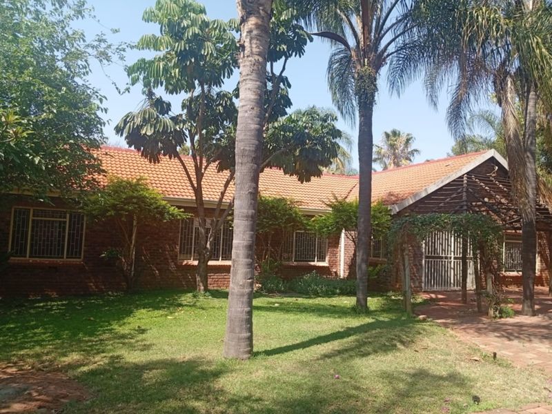 Rear view of the house featuring a brick facade, tiled roof, and a paved patio area shaded by a timber pergola.