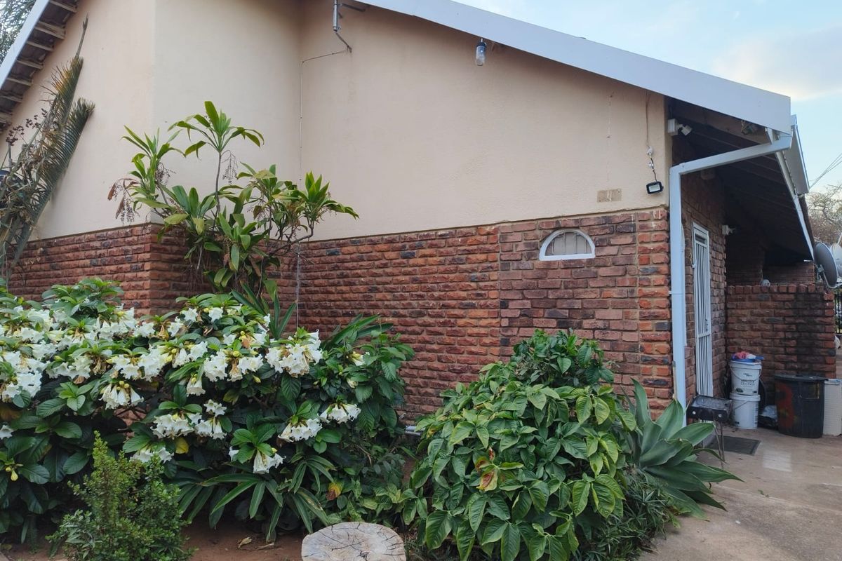 Rear exterior view of the apartment featuring a combination of face brick and plastered walls with a secure entrance gate.