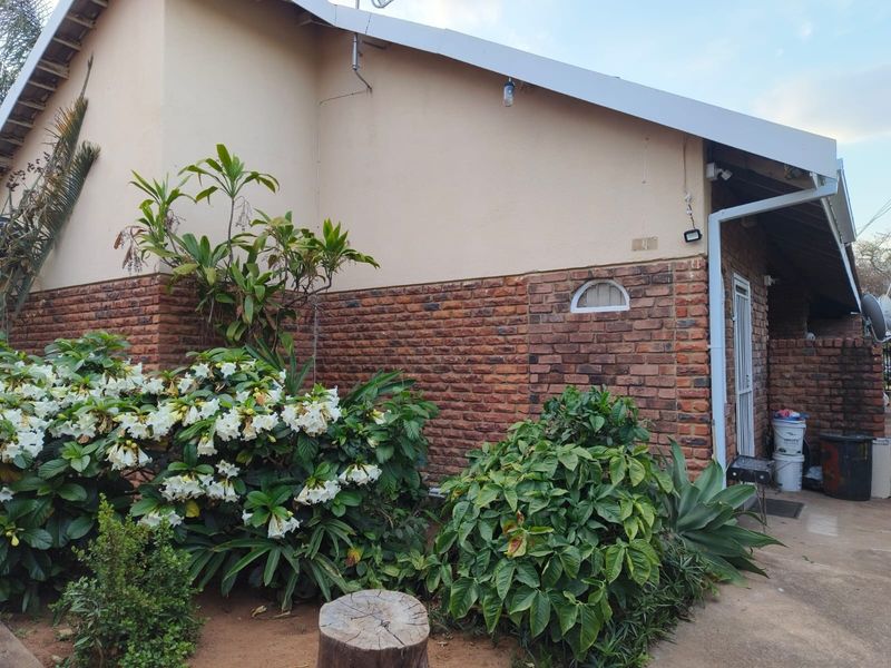 Rear exterior view of the apartment featuring a combination of face brick and plastered walls with a secure entrance gate.