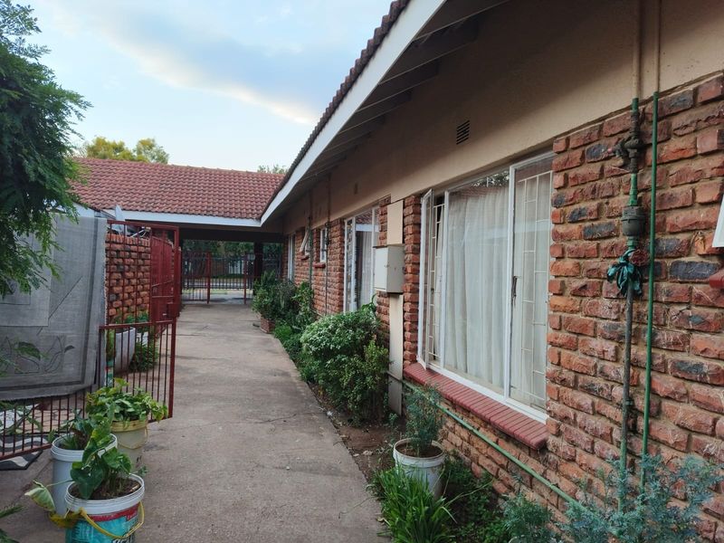 Exterior view of the apartment building featuring exposed brick walls, a tiled roof, and a concrete walkway leading to a covered entrance area.