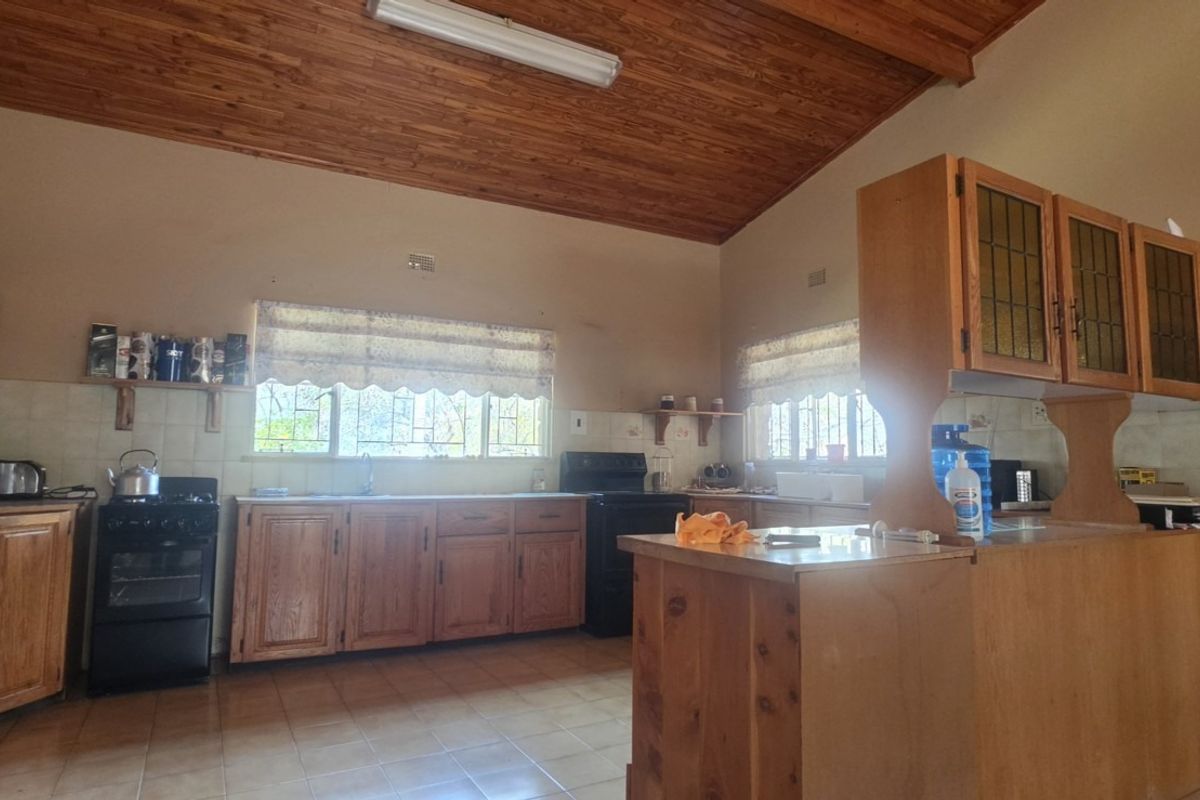 Spacious kitchen featuring wooden cabinetry, a breakfast counter, tiled backsplash, and a vaulted wooden ceiling, offering a functional layout with potential for modernization.