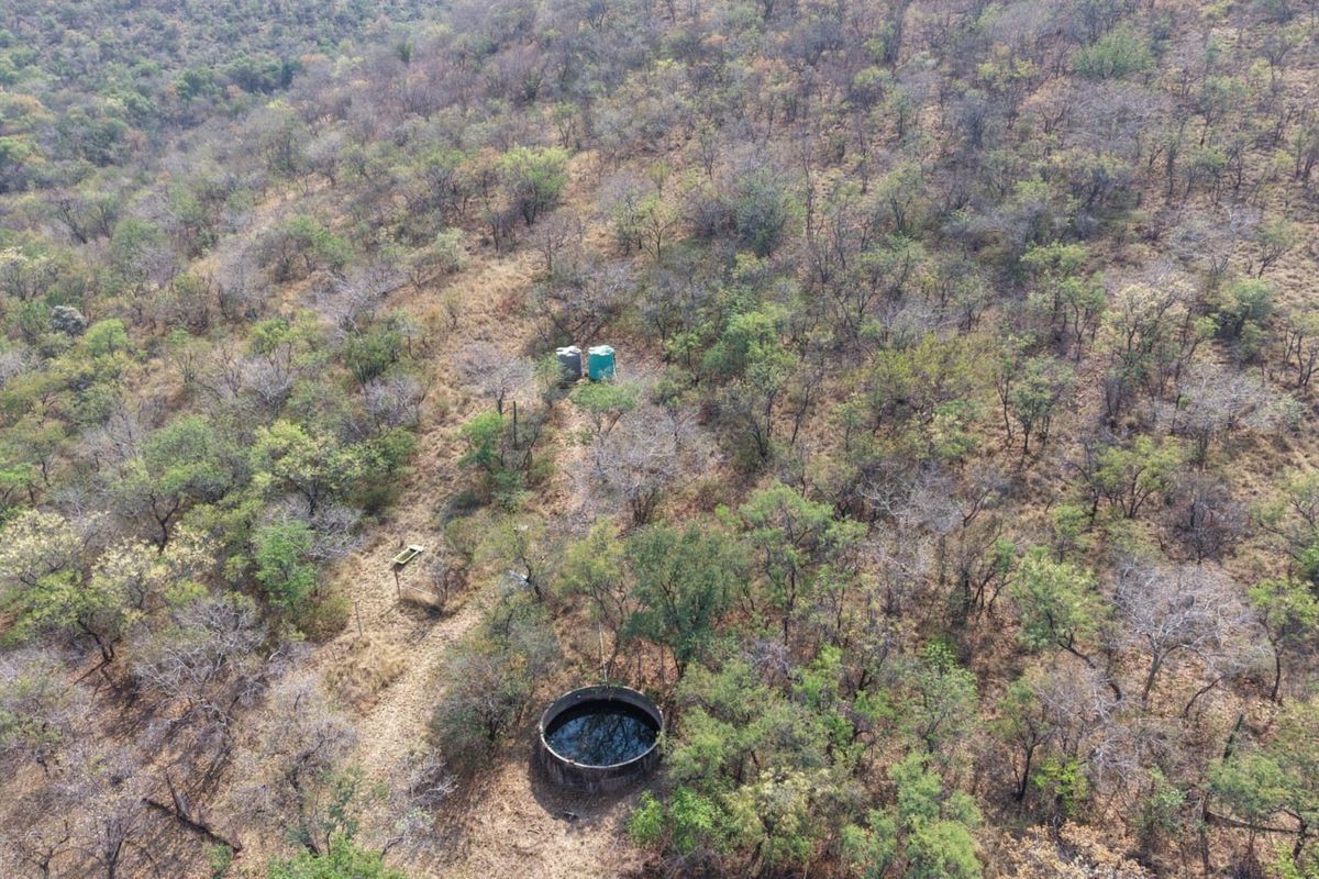 Aerial view of the farm landscape featuring a circular reservoir and water storage tanks set within the natural bushveld terrain.