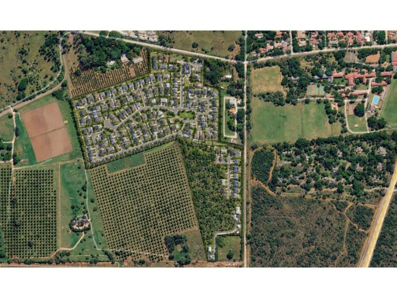 An aerial view of a residential estate development surrounded by orchards and natural landscape, showcasing the layout and surrounding environment.