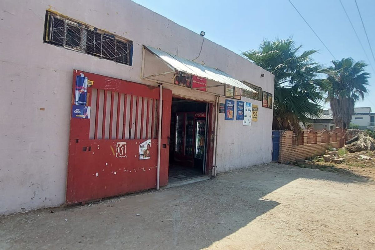 Front exterior view of a commercial-style building featuring a large red metal security gate, an awning, and security bars on the windows.