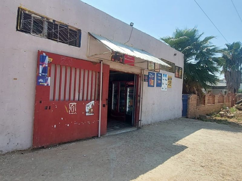Front exterior view of a commercial-style building featuring a large red metal security gate, an awning, and security bars on the windows.