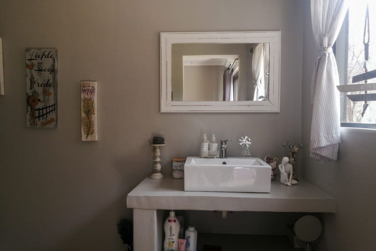 A bathroom vanity area featuring a modern white vessel sink mounted on a concrete countertop with a framed mirror above.