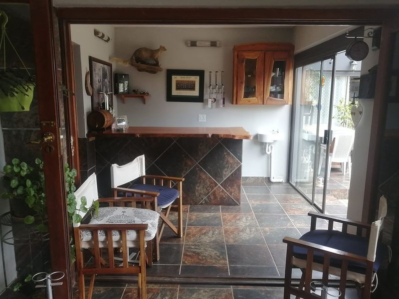 A dedicated bar area featuring a tiled counter, wall-mounted cabinetry, a small basin, and sliding glass doors leading to an outdoor patio.