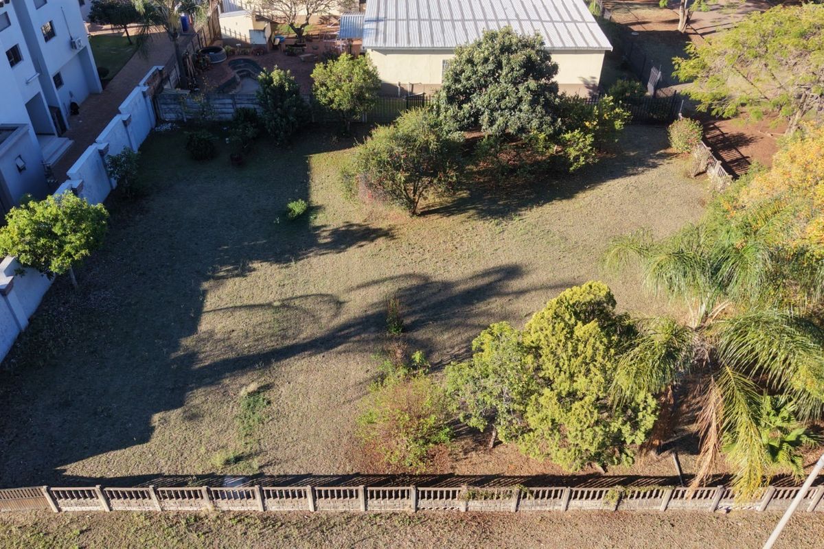 Aerial view of a residential vacant land plot featuring established trees and perimeter boundary walls.